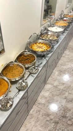 a buffet line with many different types of food on top of each other in metal pans