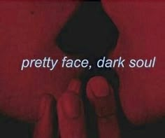 a hand holding a black object with the words pretty face, dark soul on it