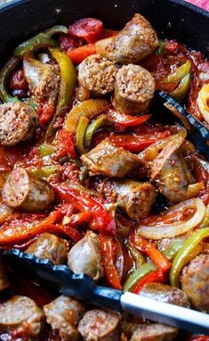 sausage and peppers are being cooked in a skillet with tongs on the side