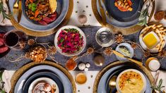 an overhead view of a table set with plates and silverware, food on it