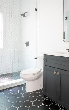 a white toilet sitting in a bathroom next to a walk in shower and black cabinets