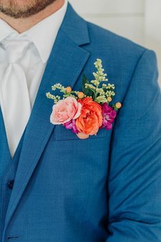 a man in a blue suit with flowers on his lapel