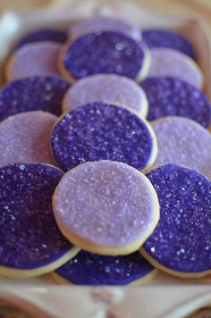 purple and gold cookies are arranged on a plate