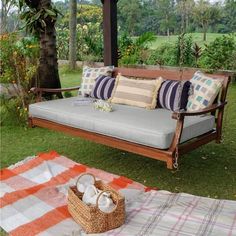 a wooden bench sitting on top of a lush green field next to a picnic table