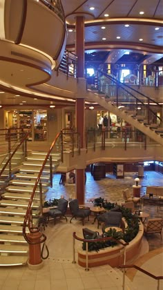 the inside of a cruise ship lobby with stairs and seating area on both sides, surrounded by glass balconies