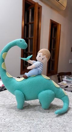 a stuffed toy sitting on top of a blue dinosaur with a boy riding it's back