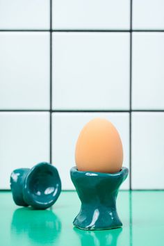 an egg sitting in a bowl on top of a table next to a tile wall