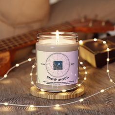 a candle sitting on top of a wooden table next to a string of lights and a guitar