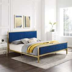 a bedroom with white walls and wood floors, blue upholstered bedspread