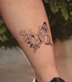 a woman's leg with a butterfly and flowers tattoo on the left side of her arm