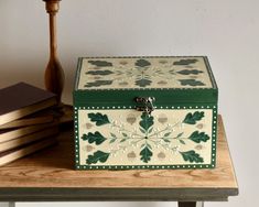 a green and white box sitting on top of a wooden table next to two books