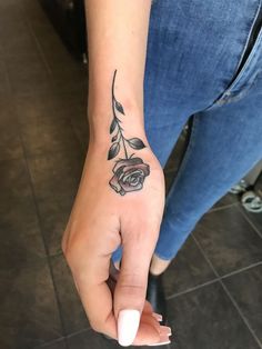 a woman's hand with a rose tattoo on it