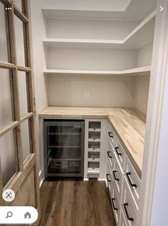 an empty walk in pantry with white cabinets and wood flooring on the bottom shelf