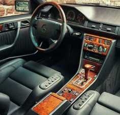 an interior view of a car with wood trim and leather seats, including the steering wheel