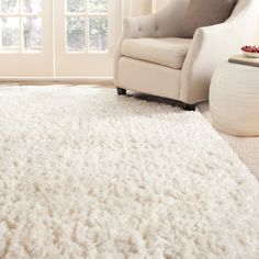 a white rug in a living room with a chair next to it and a window