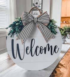 a welcome sign with a bow hanging from it's side on top of a table