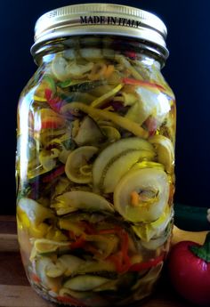 a jar filled with pickled vegetables sitting on top of a wooden table