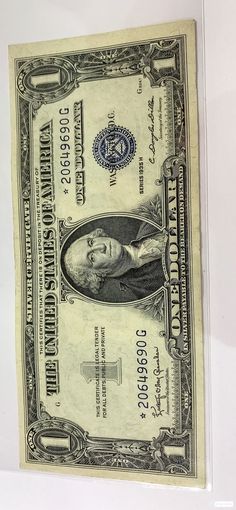 an old one dollar bill is displayed on a white surface