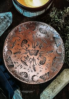 a metal plate sitting on top of a wooden table next to some rocks and plants