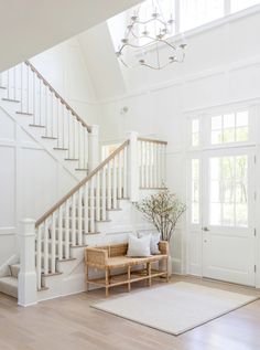 a living room filled with furniture next to a white stair case and window covered door