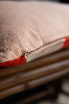 a close up of a pillow on top of a wooden bed with red piping