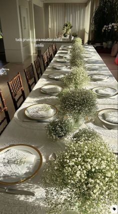 a long table is set with white flowers and place settings for the guests to sit at