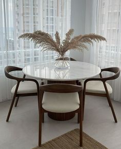 a dining room table with chairs and a vase on it