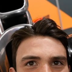 a close up of a person with headphones in front of a metal pipe and orange wall