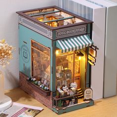 a miniature model of a small store on a table next to a vase with flowers