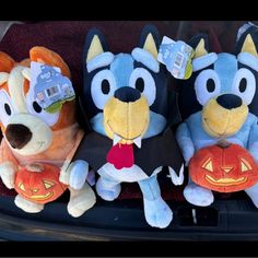 three stuffed animals sitting in the back of a car with pumpkins on their laps