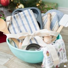 a blue bowl filled with kitchen utensils on top of a wooden table next to a christmas tree