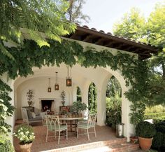 an outdoor dining area with patio furniture and potted plants on the side of it