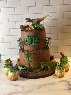 a dinosaur birthday cake with cupcakes and decorations