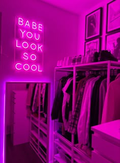 a neon sign that says babe you look so cool in front of a closet filled with clothes