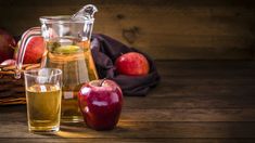 an apple cider and two glasses on a wooden table