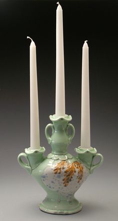 three white candles are in a green vase