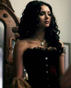 a woman in a black corset is looking at her reflection in the mirror