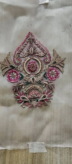 an embroidered piece of cloth with pink and green designs