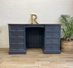 a blue desk with drawers and a gold letter on top