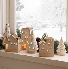 a window sill decorated with christmas lights and small houses in front of a snowy landscape