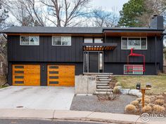 a black house with wooden garage doors and stairs