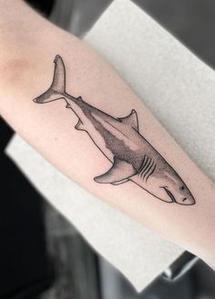 a black and white photo of a shark tattoo on the arm