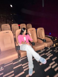 a woman is sitting on a chair in front of an empty theater with no people