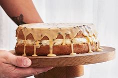 a person holding a cake with icing and toppings on it's side