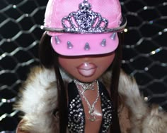 a barbie doll wearing a pink hat with silver jewels on it's face and tongue