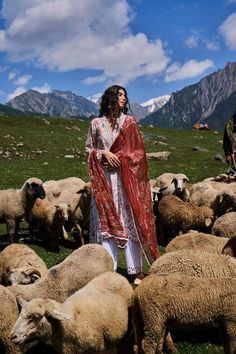 a woman standing in front of a herd of sheep