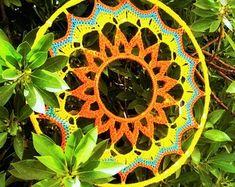 a colorful crocheted doily sitting on top of green leaves