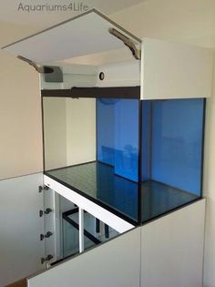 an aquarium in the corner of a room next to a stair case with glass railings