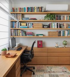 a home office with bookshelves, desk and computer on the far wall in front of an air conditioner