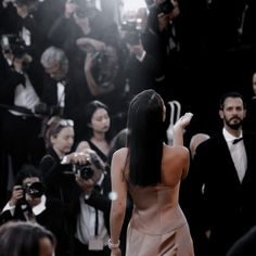 a woman in a dress is taking pictures with her cell phone at the red carpet